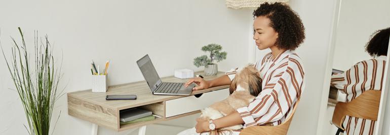Woman utilizing flexible working options by working remotely from her organized home office, engaging with a laptop.